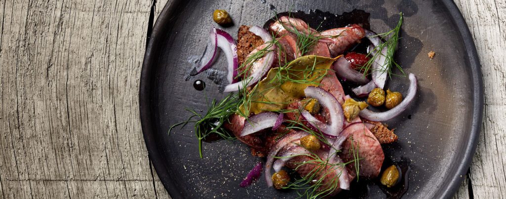 Sill marinerad med körsbär, svartpeppar, lakritsrot, crème fraiche, rödlök och kapris Gastro TopView Dish2 2740x1080 1 1024x404